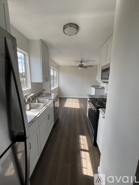 A kitchen with white cabinets and a black fridge.