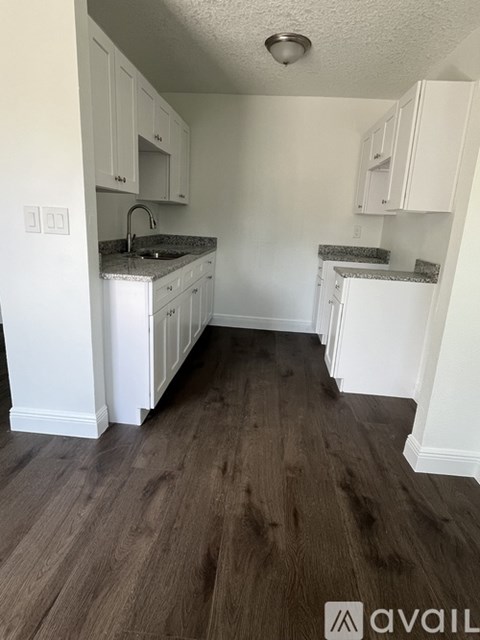 A kitchen with white cabinets and a dark wood floor.