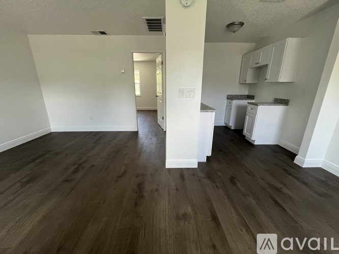 A kitchen area with white cabinets and a refrigerator.