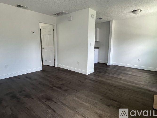 A room with wooden flooring and white walls.