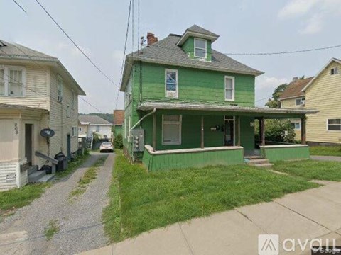 A green house with a porch is in the foreground of the image.