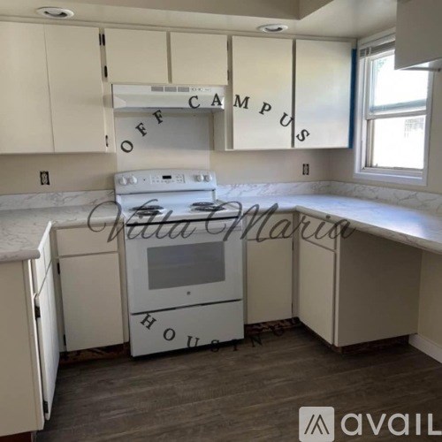 A kitchen with a white stove top oven and cabinets.