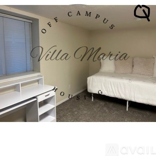 A bedroom with a bed, desk, and a wall that says "Villa Maria".