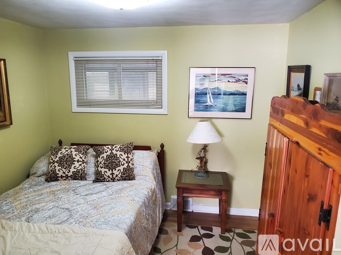 A bedroom with a bed, a nightstand with a lamp, and a painting on the wall.