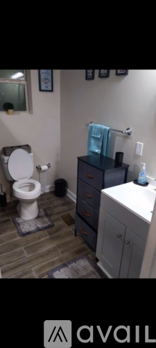 A bathroom with a toilet, sink, and cabinets.