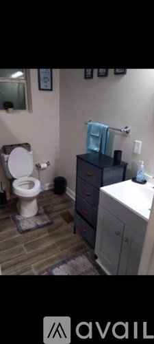 A bathroom with a toilet, sink, and cabinets.