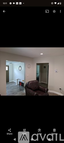 A room with a brown leather couch and a white wall.