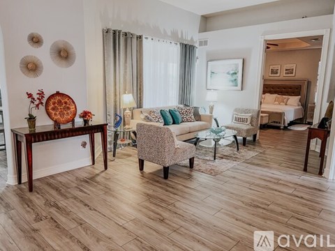 A living room with a couch, chair, and a table with a vase of flowers on it.