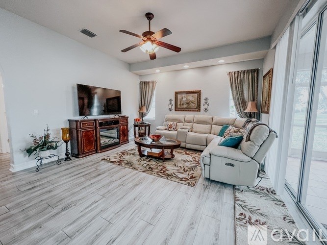 A living room with a white couch, a wooden floor, and a ceiling fan.