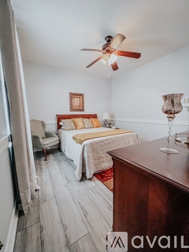 A bedroom with a bed, chair, and a ceiling fan.
