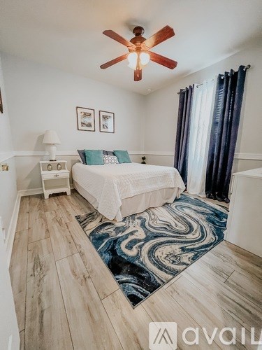 A bedroom with a bed, a ceiling fan, and a rug.