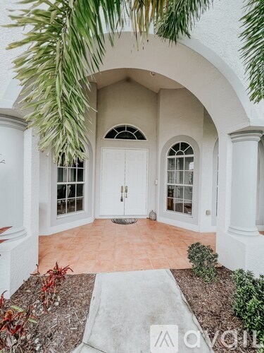 A white archway with a door and two windows.