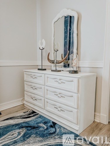 A white dresser with a mirror and two lamps on top.
