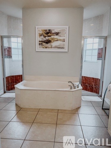 A bathroom with a white tub and a framed picture on the wall.