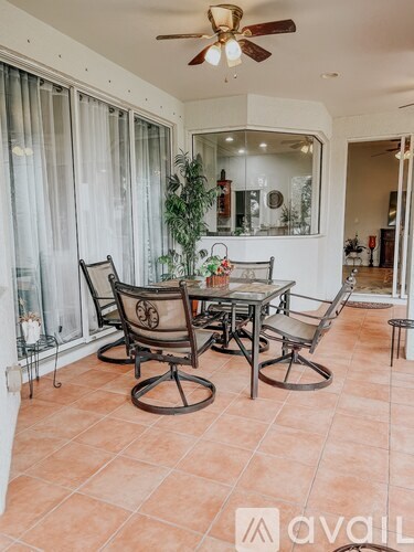 A patio with a table and chairs and a ceiling fan.