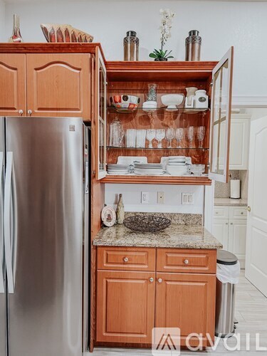A kitchen with a refrigerator and wooden cabinets.