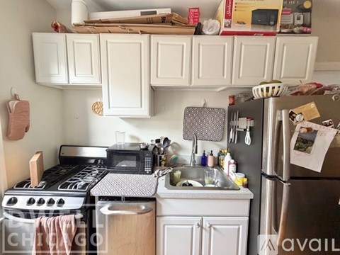A kitchen with a stainless steel refrigerator and white cabinets.