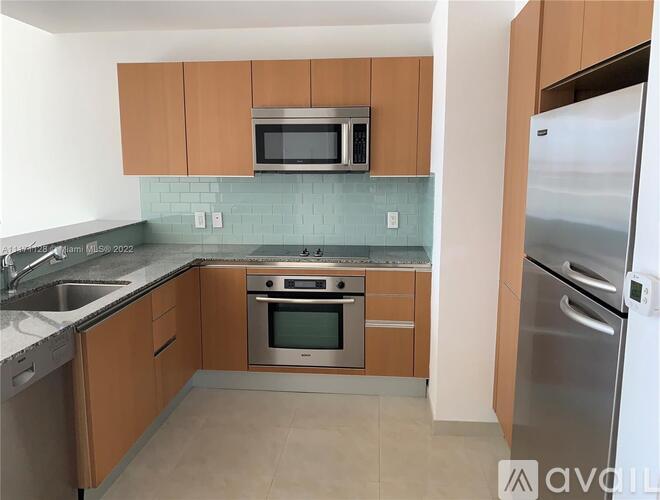 A kitchen with wooden cabinets and a stainless steel refrigerator.