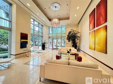 A spacious living room with a large couch and a chandelier.