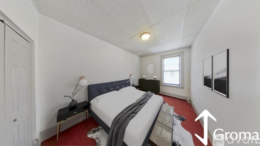 A bedroom with a bed, nightstand, and window.
