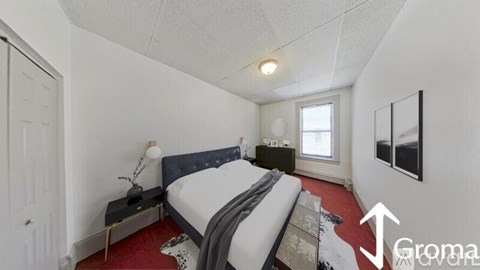 A bedroom with a bed, nightstand, and window.