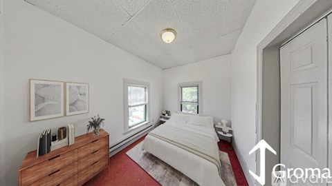 A bedroom with a white bed and a wooden dresser.