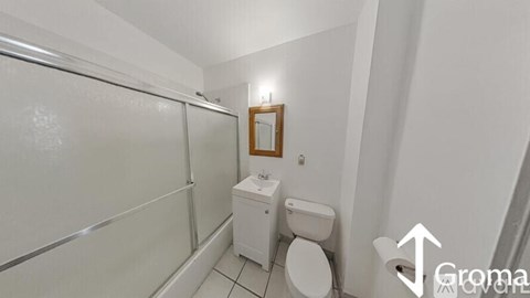 A white toilet sits next to a toilet paper holder in a small bathroom.