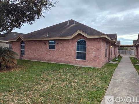 A brick house with a dark roof and a small front yard.
