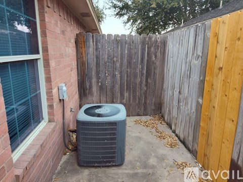 A gray air conditioner unit is outside a house.