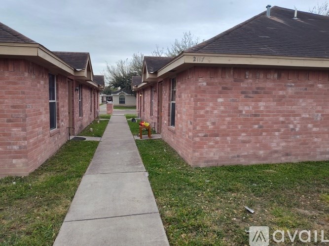 A long concrete walkway leads between two rows of identical red brick houses.