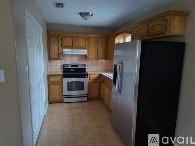 A kitchen with wooden cabinets and a black refrigerator.