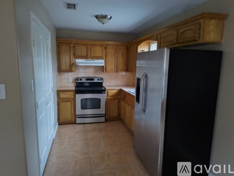 A kitchen with wooden cabinets and a black refrigerator.