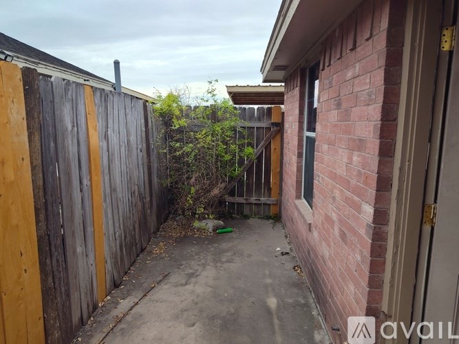 A backyard with a wooden fence and a brick building.