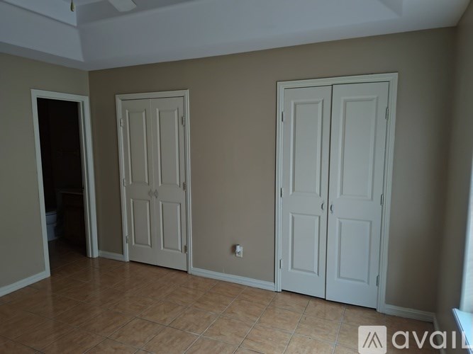 A room with two white doors and a tiled floor.