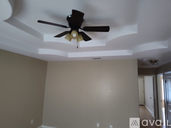 A room with a ceiling fan and a wall with a logo on it.