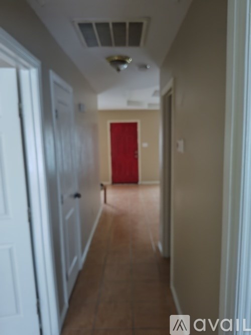 A hallway with a red door at the end.