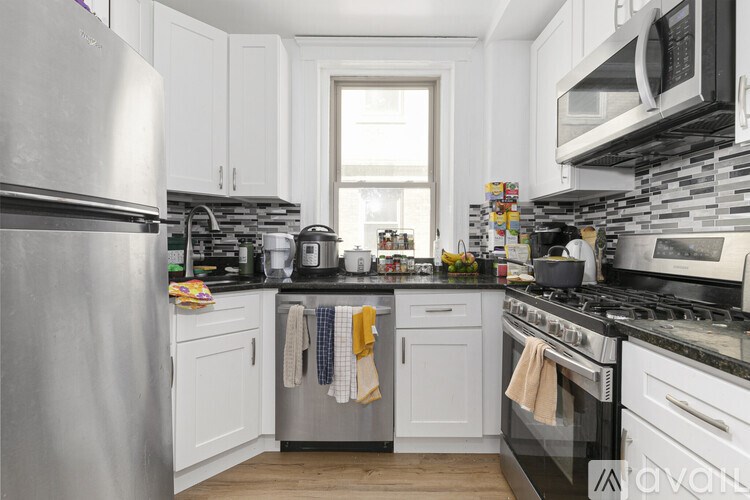 A kitchen with white cabinets and a stainless steel refrigerator.