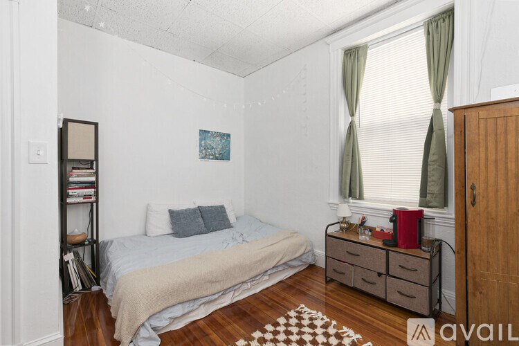 A bedroom with a bed, nightstand, and a window with green curtains.