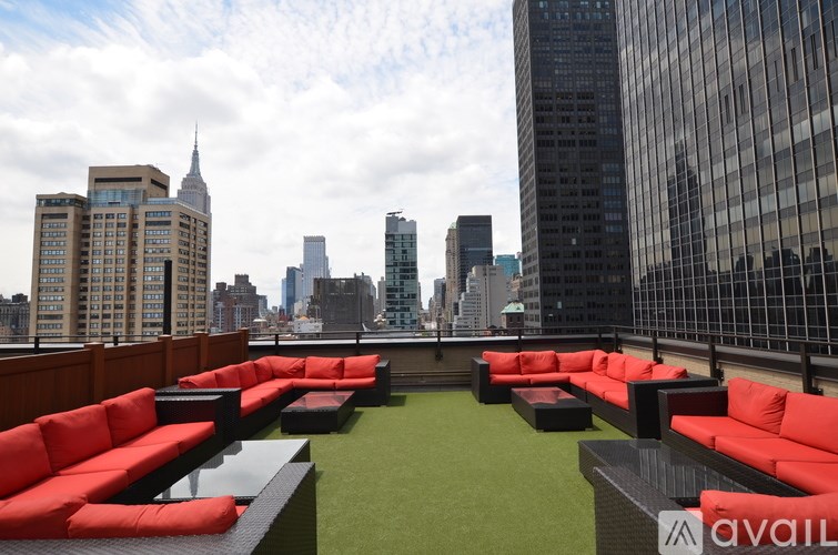 A rooftop patio with red couches and a view of the city skyline.