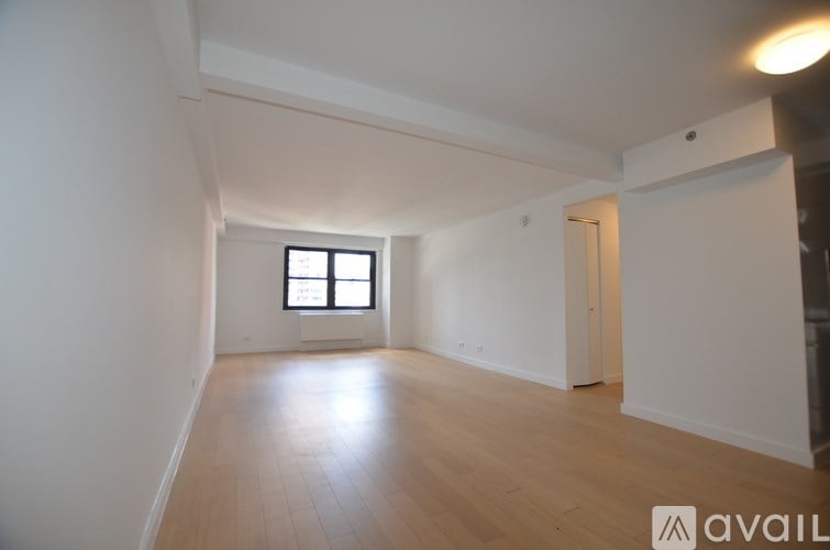 A spacious room with wooden flooring and a window.