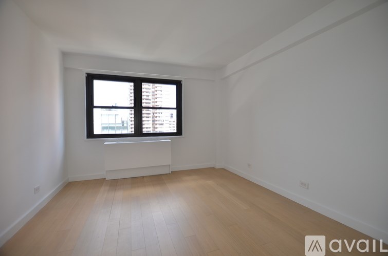 A room with a window and wooden flooring is available for rent.