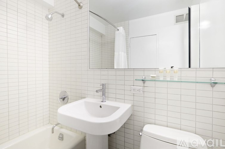 A white sink in a white tiled bathroom.