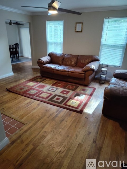 A living room with a brown leather couch and a rug.