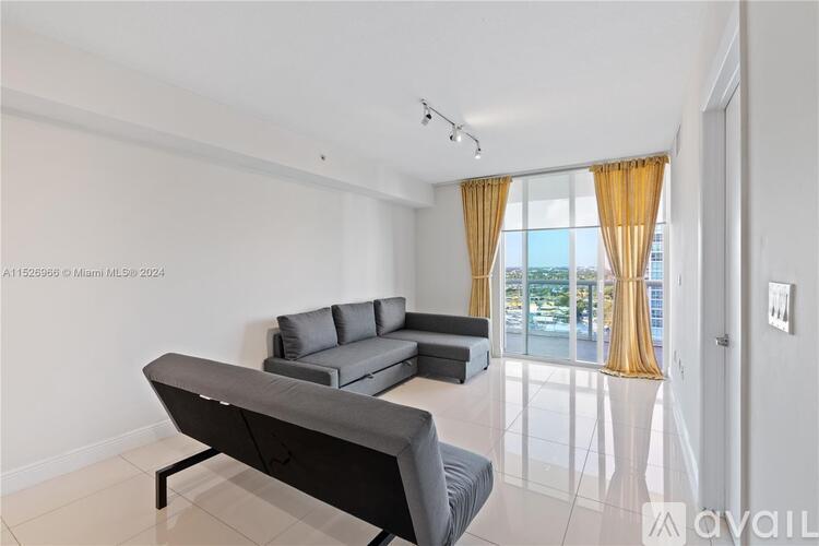 A modern living room with a grey sofa and a large window with yellow curtains.