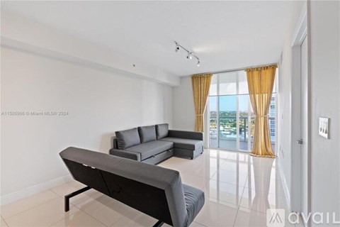 A modern living room with a grey sofa and a large window with yellow curtains.