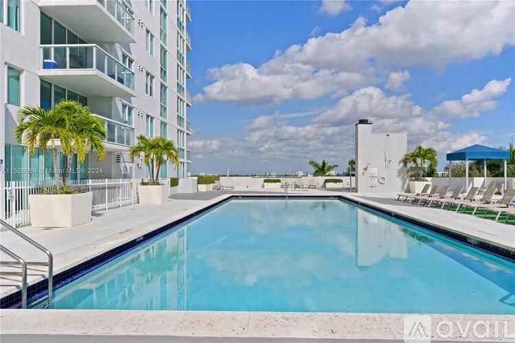 A swimming pool in front of a white building with palm trees.