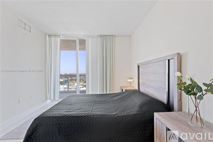A bedroom with a large bed and a view of the city through the window.