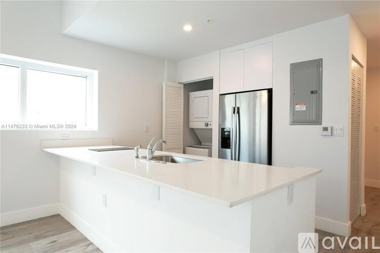 A modern kitchen with white countertops and stainless steel appliances.