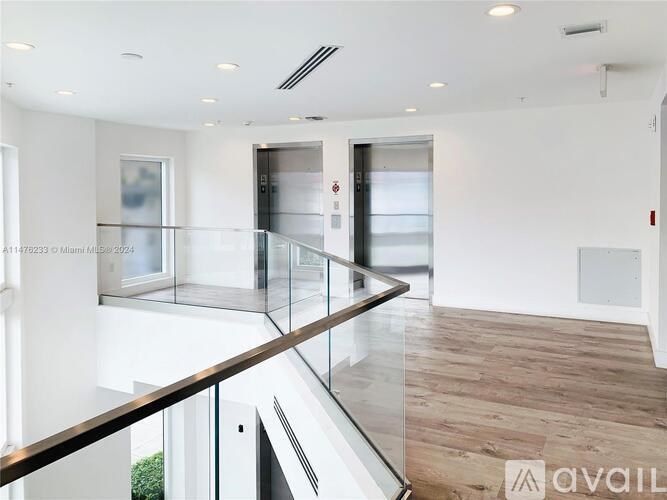 A modern interior space with a glass railing and wooden flooring.