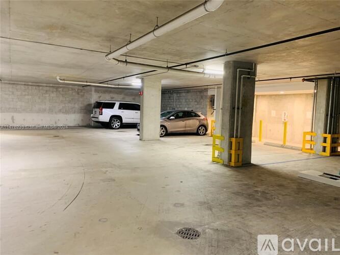 A parking garage with a white van and a black car.
